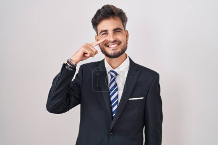 Photo for Young hispanic man with tattoos wearing business suit and tie pointing with hand finger to face and nose, smiling cheerful. beauty concept - Royalty Free Image