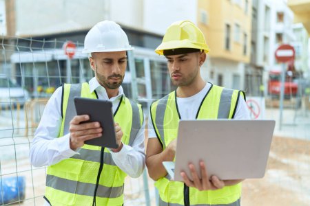 Photo for Two hispanic men architects using touchpad and laptop working at street - Royalty Free Image