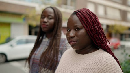 Téléchargez les photos : Deux amis afro-américains avec une expression sérieuse debout ensemble dans la rue - en image libre de droit