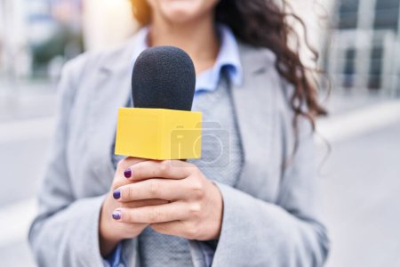 Téléchargez les photos : Jeune journaliste hispanique travaillant au microphone dans la rue - en image libre de droit