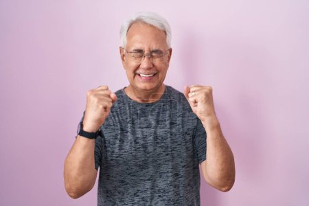 Photo for Middle age man with grey hair standing over pink background excited for success with arms raised and eyes closed celebrating victory smiling. winner concept. - Royalty Free Image