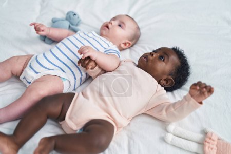 Téléchargez les photos : Deux adorables bébés couchés sur le lit dans la chambre - en image libre de droit