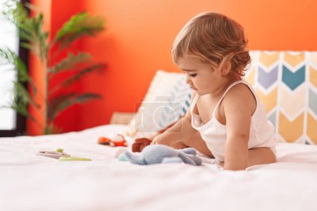 Photo for Adorable hispanic toddler sitting on bed with relaxed expression at bedroom - Royalty Free Image