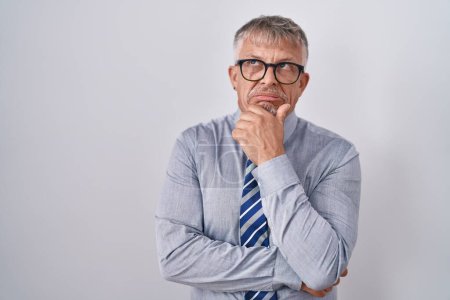 Photo for Hispanic business man with grey hair wearing glasses thinking worried about a question, concerned and nervous with hand on chin - Royalty Free Image