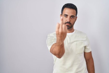 Foto de Hispanic man with beard standing over isolated background showing middle finger, impolite and rude fuck off expression - Imagen libre de derechos