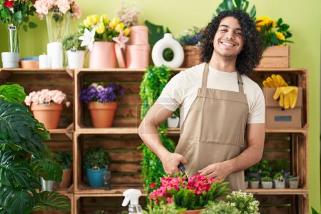 Téléchargez les photos : Jeune homme latin fleuriste usines de découpe à la boutique de fleurs - en image libre de droit