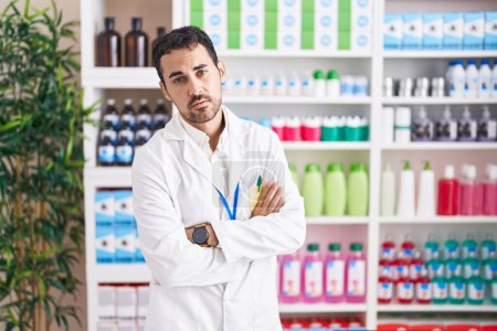 Téléchargez les photos : Handsome hispanic man working at pharmacy drugstore looking sleepy and tired, exhausted for fatigue and hangover, lazy eyes in the morning. - en image libre de droit