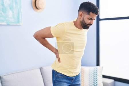 Photo for Young arab man suffering for backache standing at home - Royalty Free Image