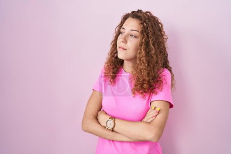 Téléchargez les photos : Jeune femme caucasienne debout sur fond rose regardant sur le côté avec les bras croisés convaincus et confiants - en image libre de droit