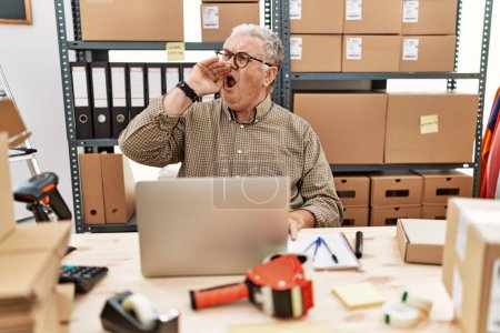 Photo for Senior caucasian man working at small business ecommerce with laptop shouting and screaming loud to side with hand on mouth. communication concept. - Royalty Free Image