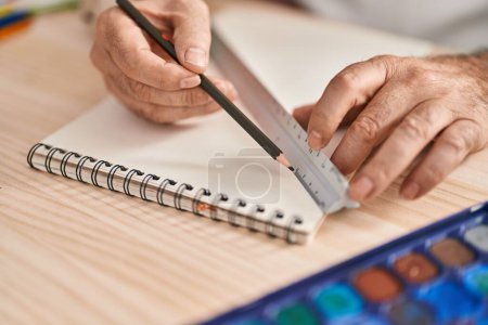 Photo for Middle age grey-haired man artist drawing line on notebook using tape measure at laboratory - Royalty Free Image