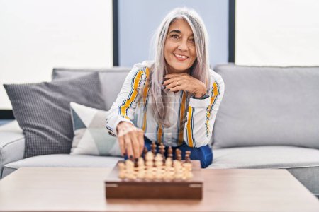 Téléchargez les photos : Middle age grey-haired woman playing chess game sitting on sofa at home - en image libre de droit