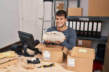 Photo for Young hispanic man ecommerce business worker preparing clothes package at office - Royalty Free Image