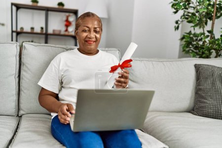 Téléchargez les photos : Femme afro-américaine senior titulaire d'un diplôme ayant appel vidéo à la maison - en image libre de droit