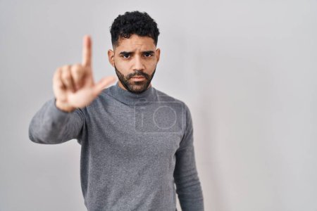 Téléchargez les photos : Homme hispanique avec la barbe debout sur fond blanc pointant avec le doigt vers le haut et l'expression en colère, ne montrant aucun geste - en image libre de droit