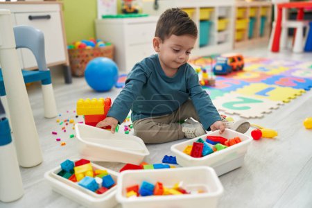 Photo for Adorable hispanic boy playing with construction blocks sitting on floor at kindergarten - Royalty Free Image