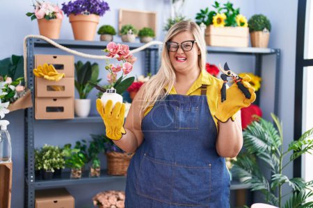 Photo for Caucasian plus size woman working at florist shop winking looking at the camera with sexy expression, cheerful and happy face. - Royalty Free Image