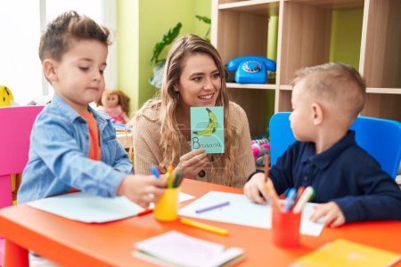 Photo for Teacher with boys sitting on table having language lesson at kindergarten - Royalty Free Image