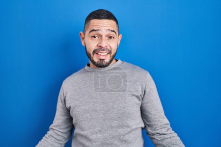 Téléchargez les photos : Hispanic man standing over blue background smiling cheerful with open arms as friendly welcome, positive and confident greetings - en image libre de droit