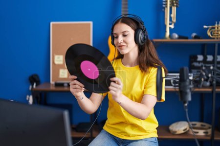 Téléchargez les photos : Young woman musician listening song holding vinyl disc at music studio - en image libre de droit