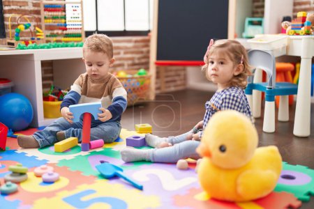 Foto de Dos niños jugando con bloques de construcción sentados en el suelo en el jardín de infantes - Imagen libre de derechos