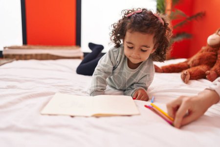 Photo for Adorable hispanic girl drawing on notebook lying on sofa at bedroom - Royalty Free Image