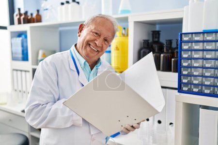 Foto de Hombre mayor con uniforme científico leyendo documento en el laboratorio - Imagen libre de derechos