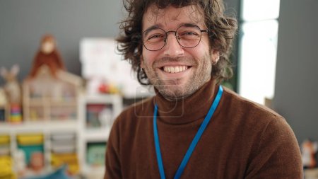 Téléchargez les photos : Young hispanic man preschool teacher smiling confident standing at kindergarten - en image libre de droit