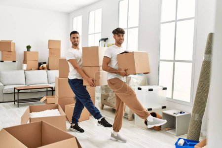 Photo for Two hispanic men couple smiling confident holding cardboard boxes at new home - Royalty Free Image