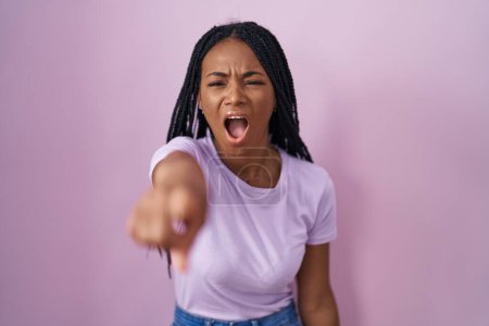 Photo for African american woman with braids standing over pink background pointing displeased and frustrated to the camera, angry and furious with you - Royalty Free Image