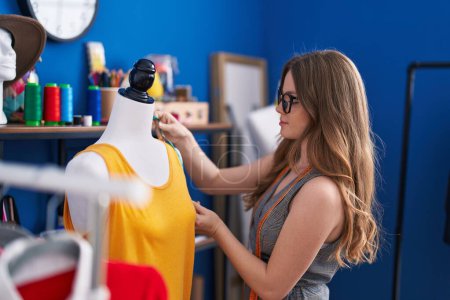 Téléchargez les photos : Young woman tailor measuring t shirt at clothing factory - en image libre de droit