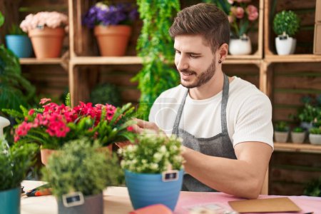 Téléchargez les photos : Jeune caucasien homme fleuriste souriant confiant toucher plante à la boutique de fleurs - en image libre de droit