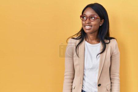 Foto de African young woman wearing glasses smiling looking to the side and staring away thinking. - Imagen libre de derechos