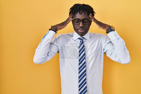 Photo for African man with dreadlocks standing over yellow background with hand on head for pain in head because stress. suffering migraine. - Royalty Free Image