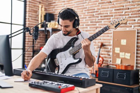 Téléchargez les photos : Jeune artiste arabe composer chanson jouer de la guitare électrique au studio de musique - en image libre de droit