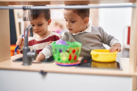 Foto de Dos niños jugando con la cocina de juego de pie en el jardín de infantes - Imagen libre de derechos