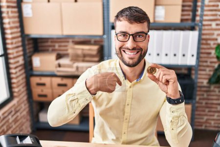 Foto de Handsome hispanic man working at small business ecommerce holding bitcoin pointing finger to one self smiling happy and proud - Imagen libre de derechos
