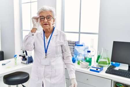 Foto de Mujer mayor de cabello gris con uniforme científico de pie en el laboratorio - Imagen libre de derechos