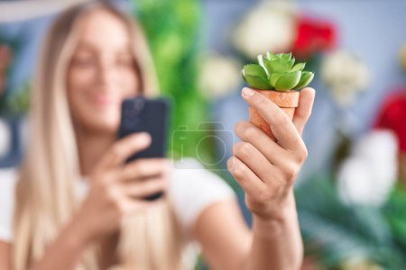 Téléchargez les photos : Jeune belle hispanique femme fleuriste faire une photo à planter par smartphone à la boutique de fleurs - en image libre de droit