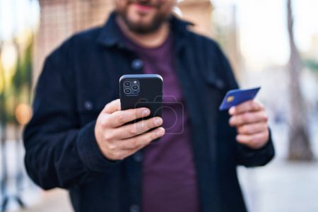 Téléchargez les photos : Jeune homme hispanique utilisant smartphone et carte de crédit à la rue - en image libre de droit
