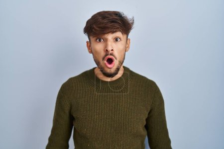 Téléchargez les photos : Arab man with beard standing over blue background afraid and shocked with surprise expression, fear and excited face. - en image libre de droit