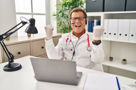 Téléchargez les photos : Médecin-chef travaillant sur rendez-vous en ligne célébrant surpris et étonnés pour le succès avec les bras levés et les yeux fermés. concept gagnant. - en image libre de droit