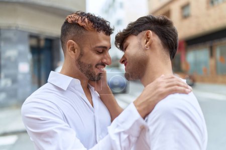 Foto de Two hispanic men couple smiling confident hugging each other at street - Imagen libre de derechos