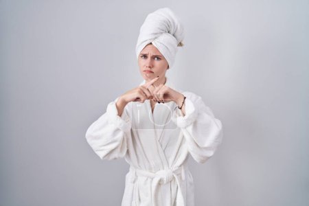 Téléchargez les photos : Blonde caucasienne femme portant peignoir rejet expression croisement doigts faire signe négatif - en image libre de droit
