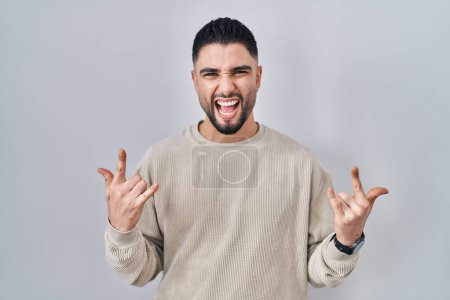 Téléchargez les photos : Young handsome man standing over isolated background shouting with crazy expression doing rock symbol with hands up. music star. heavy music concept. - en image libre de droit