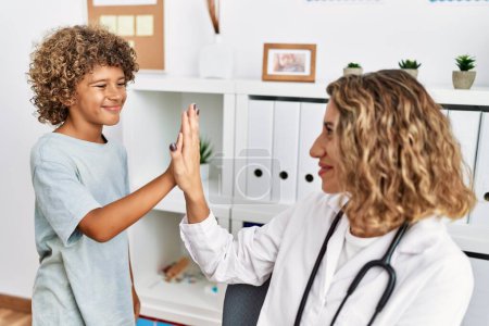 Photo for Mother and son smiling confident high five raised up hands at clinic - Royalty Free Image