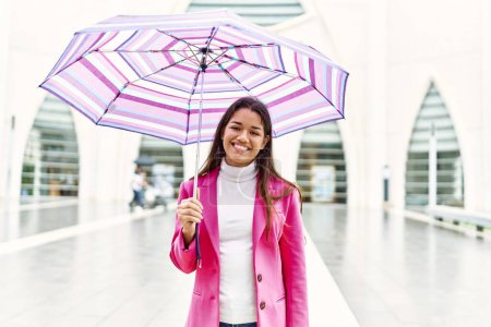 Photo for Young latin woman smiling confident holding umbrella standing at street - Royalty Free Image