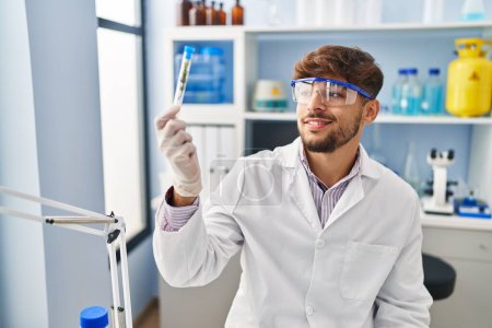 Téléchargez les photos : Young arab man scientist holding plant test tube at laboratory - en image libre de droit