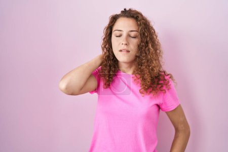 Photo for Young caucasian woman standing over pink background suffering of neck ache injury, touching neck with hand, muscular pain - Royalty Free Image