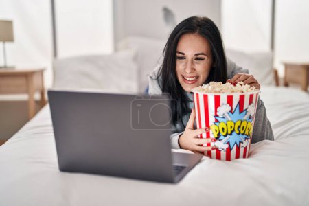 Photo for Young caucasian woman watching movie on laptop lying on bed at bedroom - Royalty Free Image